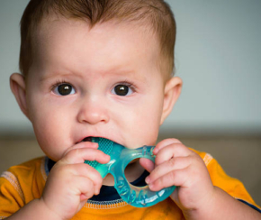 Baby chewing on teething ring toy