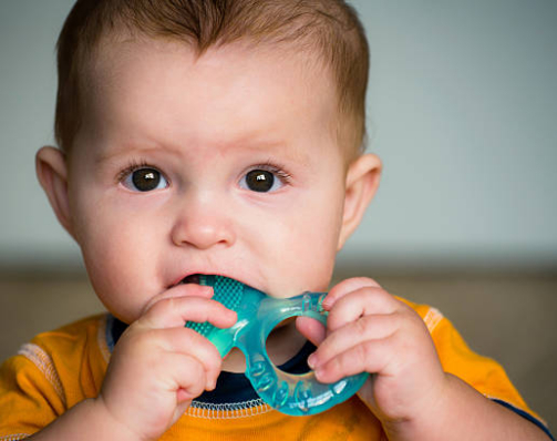 Baby chewing on teething ring toy